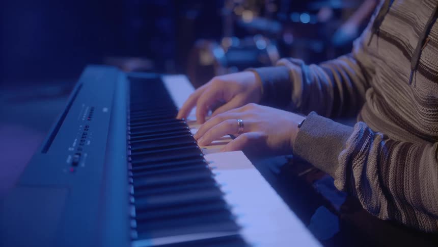 A group of people playing instruments while performing under colored lighting