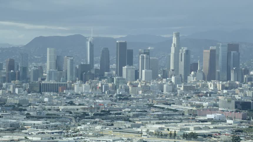 Sprawling city borders mountain range under cloudy sky