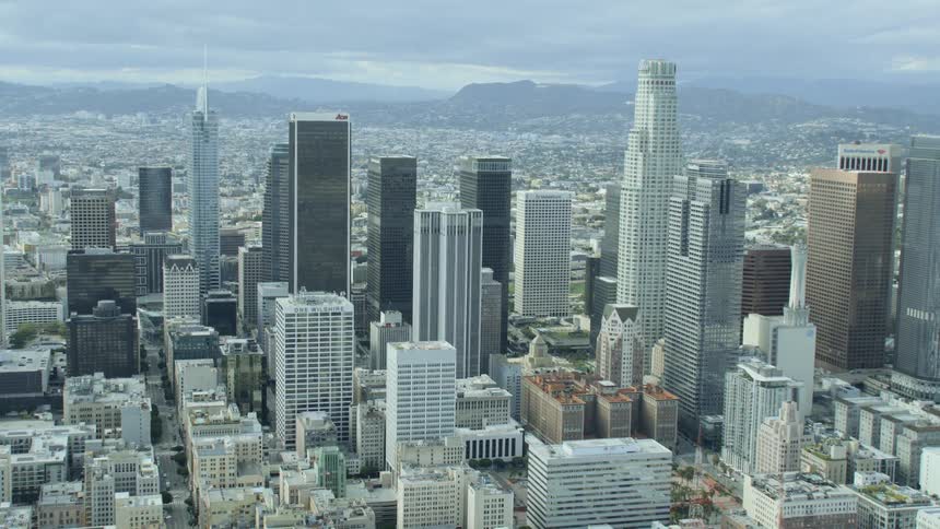 City sprawl densely covers wide area between mountains on a foggy day