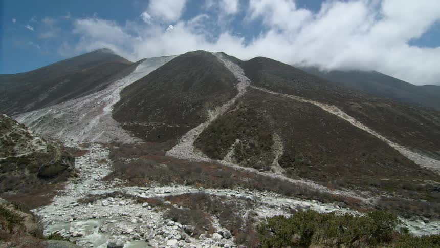 Clouds move in the sky behind a mountain