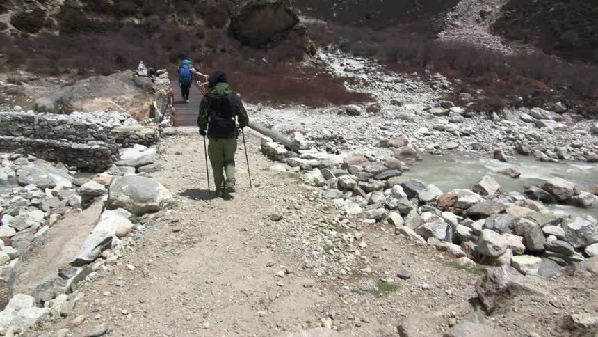 People hike over a bridge