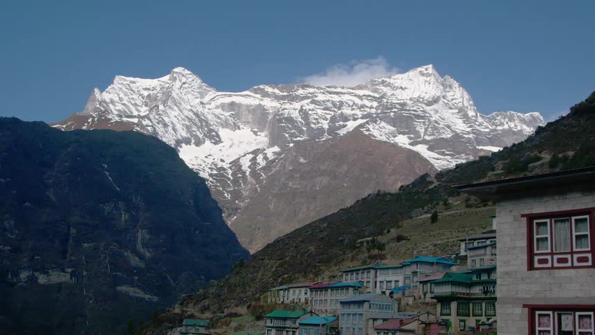 A neighborhood sits below a snow covered mountain range