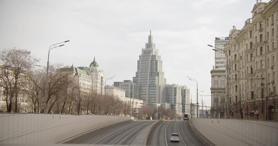 A vehicle travels the road leading to a city with a thin coating of snow around