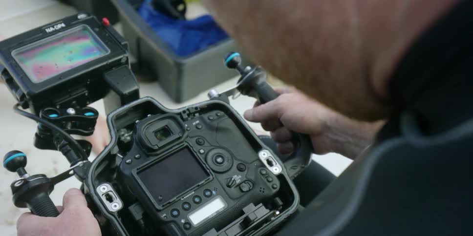 A man adjusting a large camera