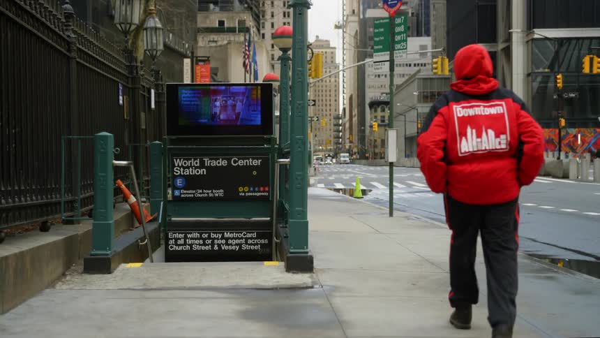 A man walks down the street as cars drive by an empty World Trade Center