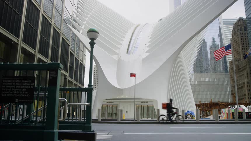 A man rides his bike down the street in front of empty Oculus at World Trade Center
