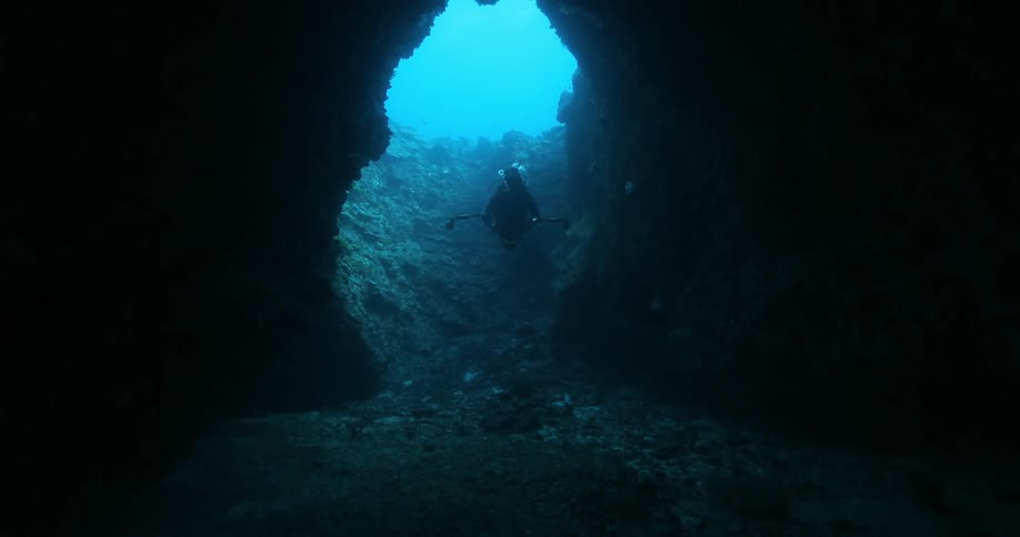 A scuba diver floats down into an underwater cave