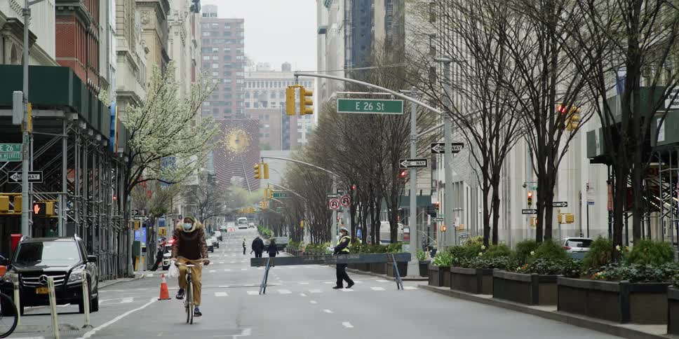 The city is empty with some people traveling wearing masks