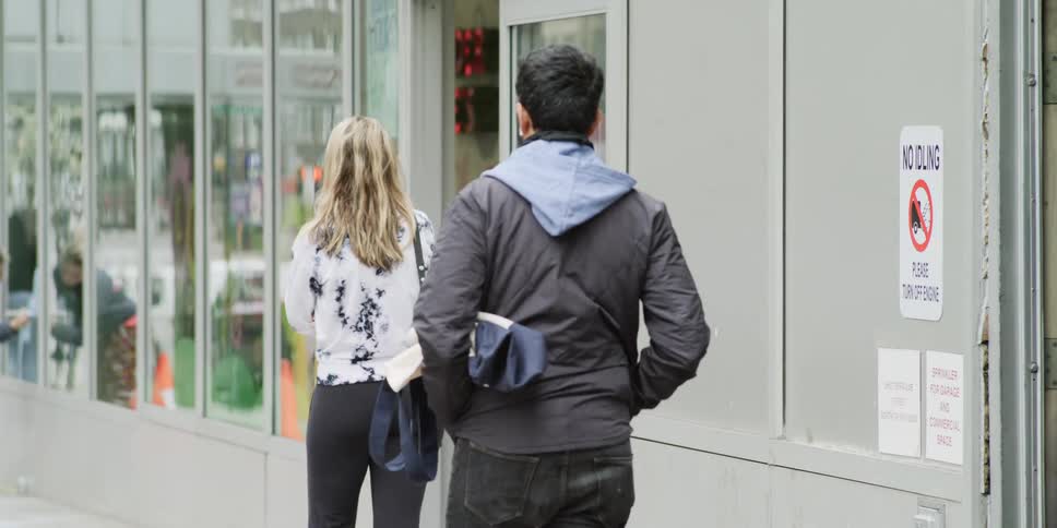 People practice social distancing waiting to enter a shop