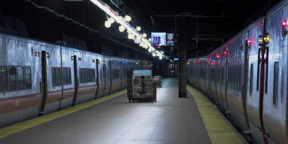 Two subway trains parked on both sides of a deserted platform with a video screen displaying messages