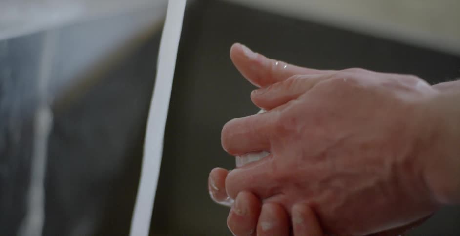 A person washes their hands in a sink with soap
