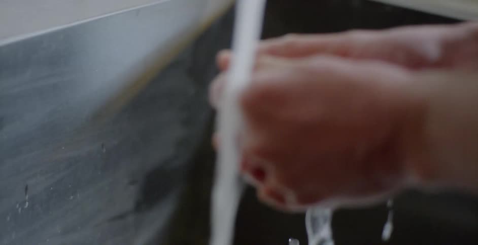 A person washes their hands under the water