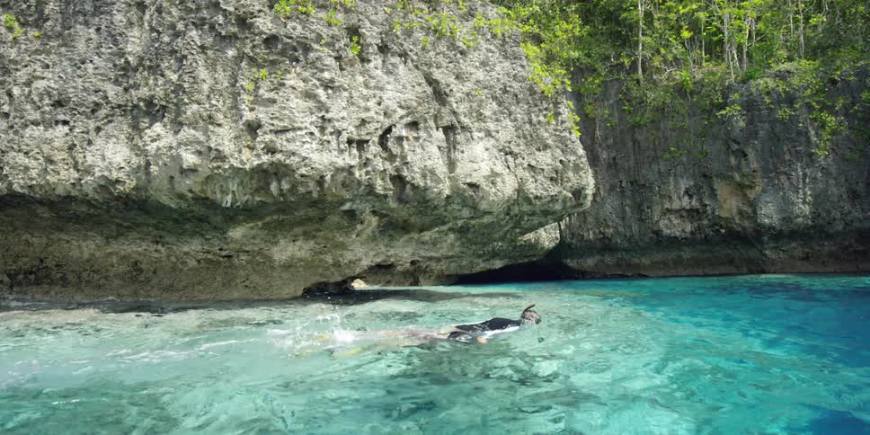 A man snorkels under a rock