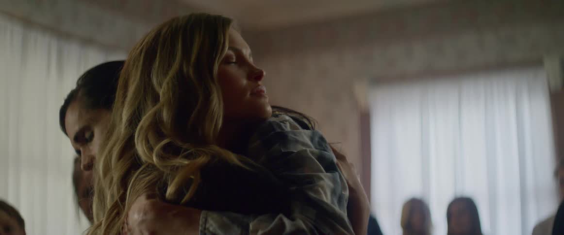 Two women hug while other people look on