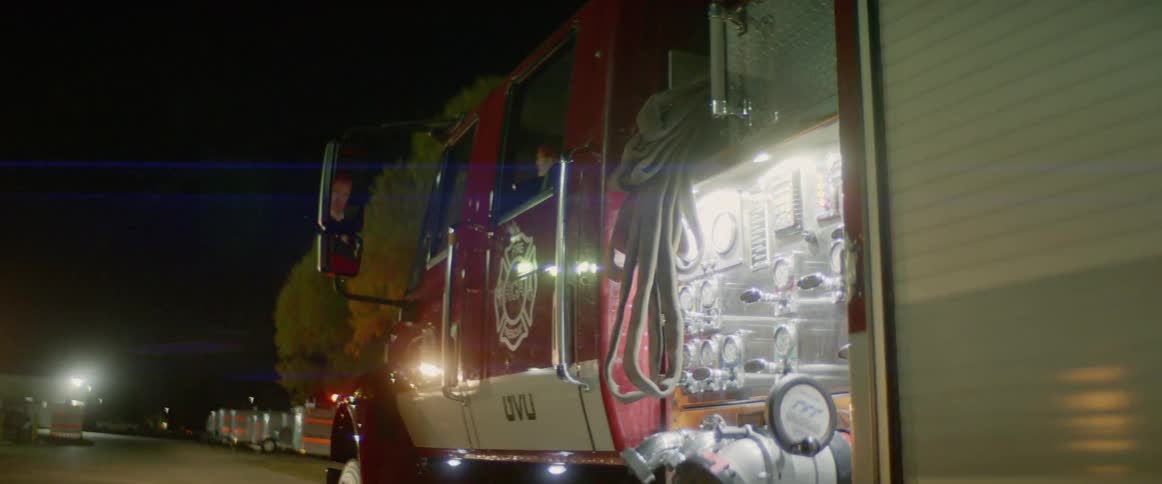 A fire engine with flashing lights parked on a road at night