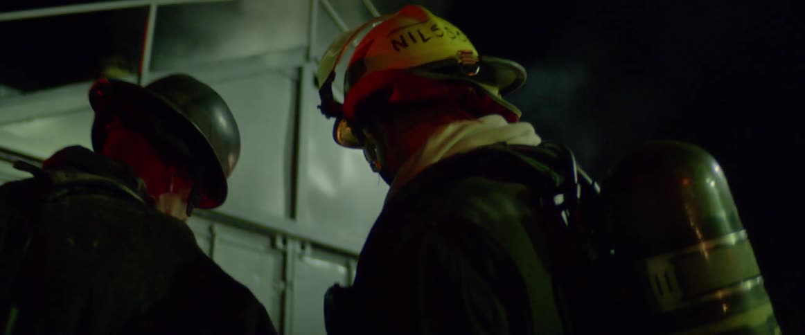 Firemen examine smoking building at night