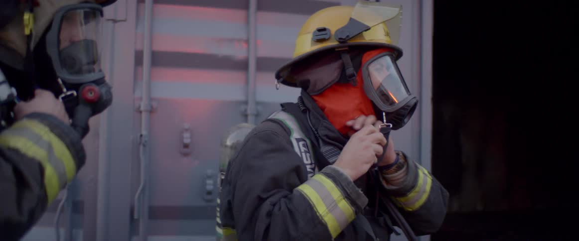 Firemen are outside a building and wearing protective gear