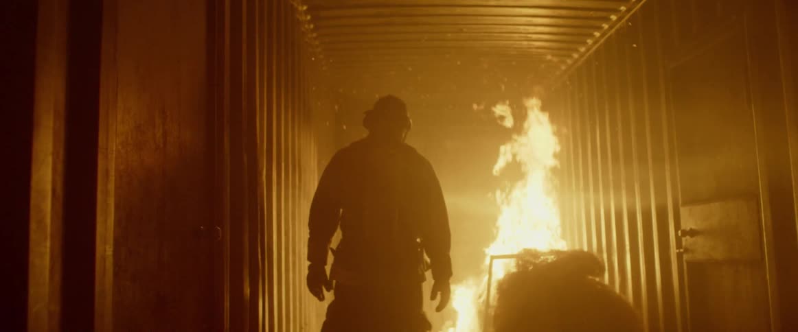 A firefighter walking towards a fire indoors