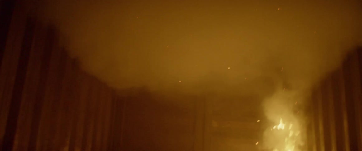 Fire burns in interior corner as person looks on
