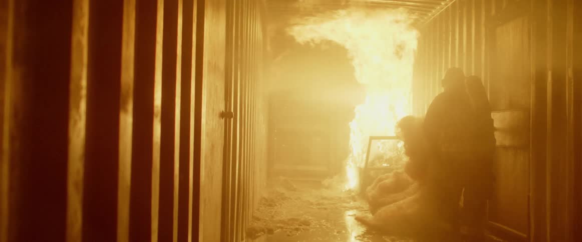 Firefighter pulls netted material away from fire roaring in corridor
