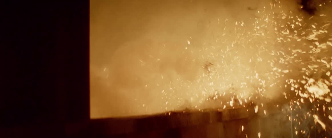 A fire burning by a window in the dark with embers flying