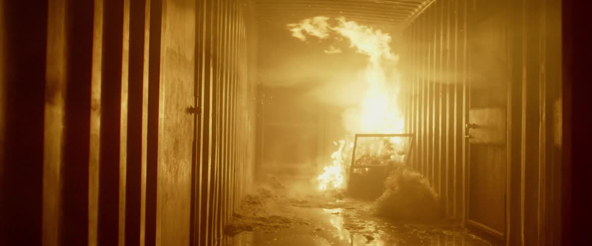 A fire burns in the corner of a container
