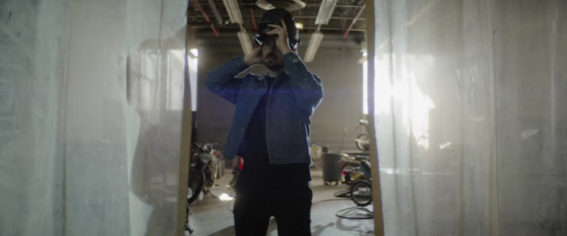 A man walks to the opening and closes the welding hat