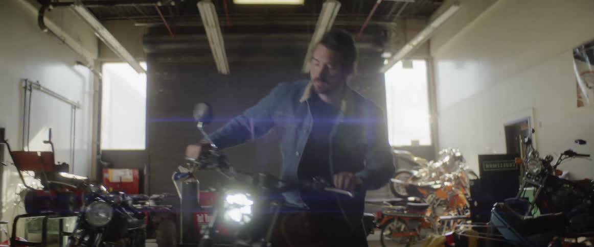 Man gets on a motorcycle as it sits in a garage