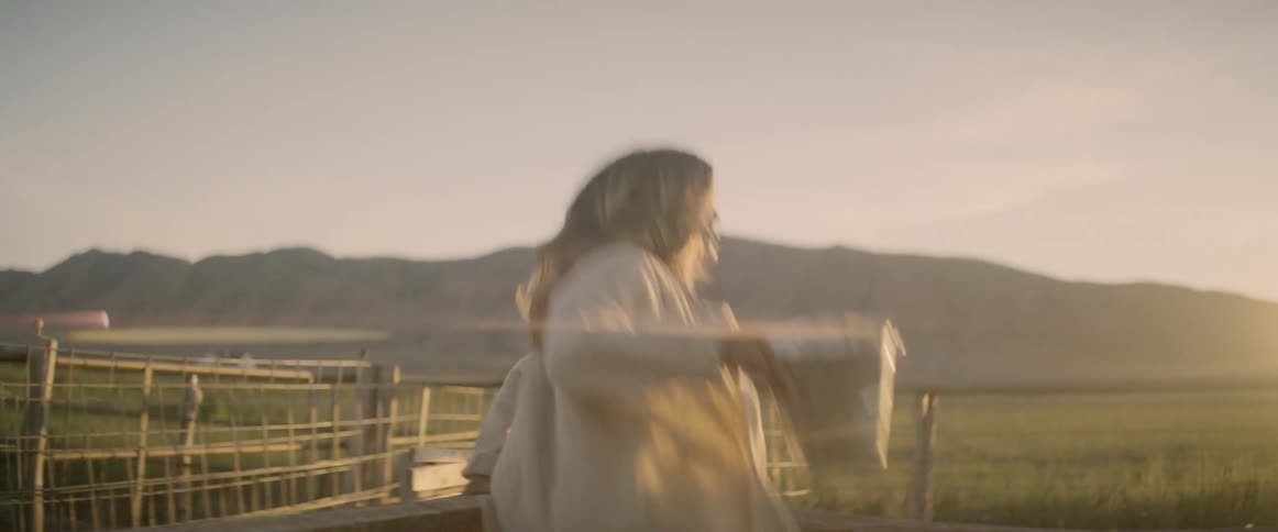 A woman climbs over the fence on the farm