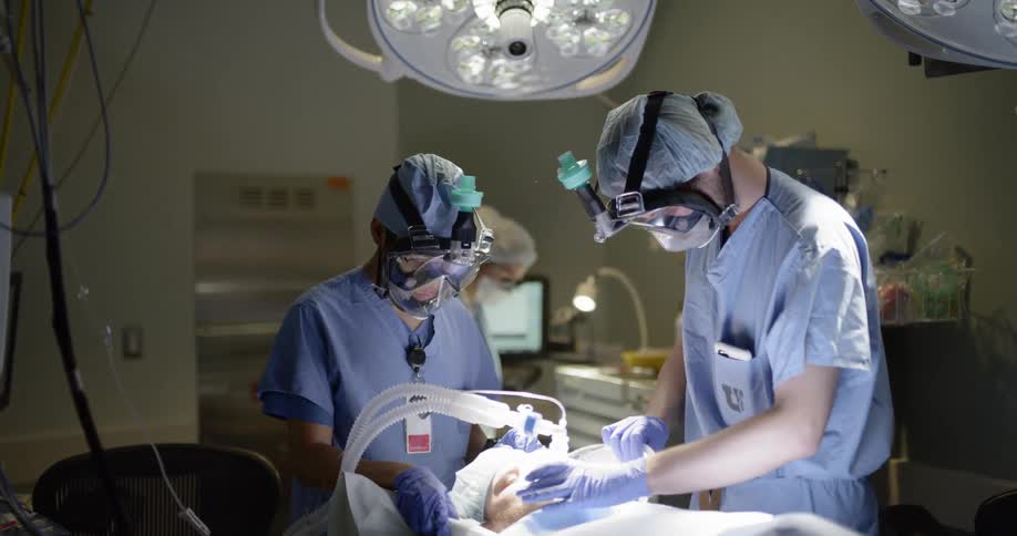 A patient is in surgery and is being operated on by surgeons