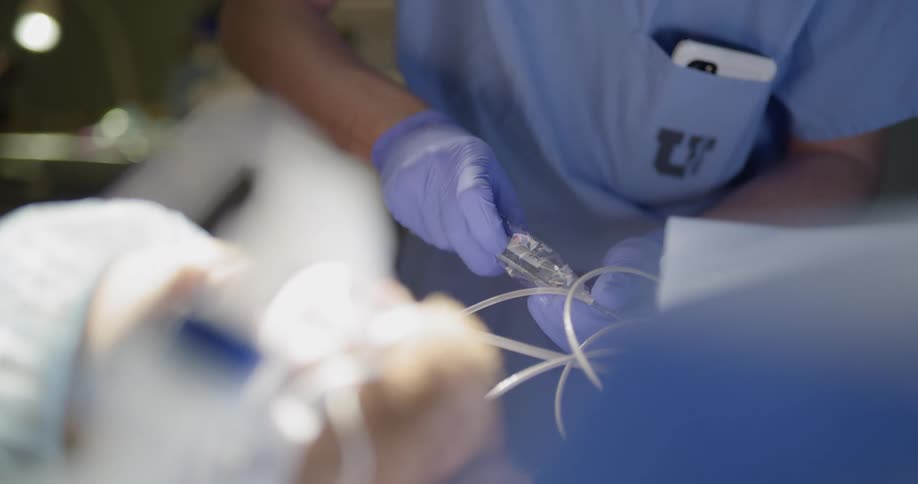 A patient lies on a table as a doctor adjusts a syringe