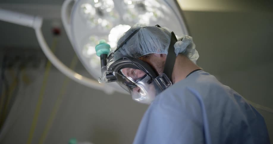 Medical professional in scrubs prepares in operating room under lights