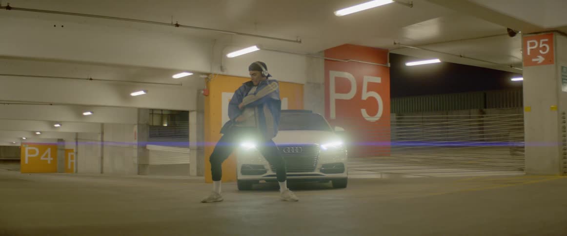 A teenager dances in a parking garage
