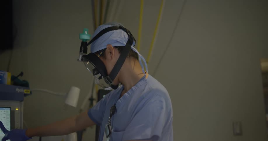 A doctor looks at a screen while wearing a respiratory mask.
