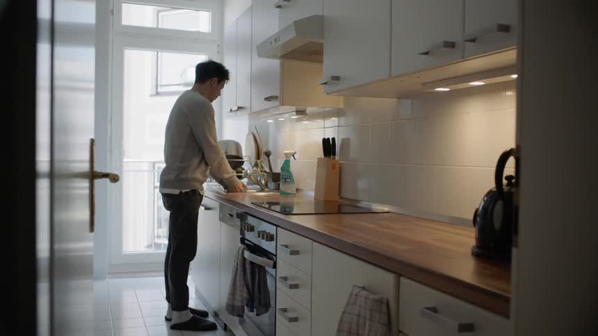 Man washes hands in kitchen sink