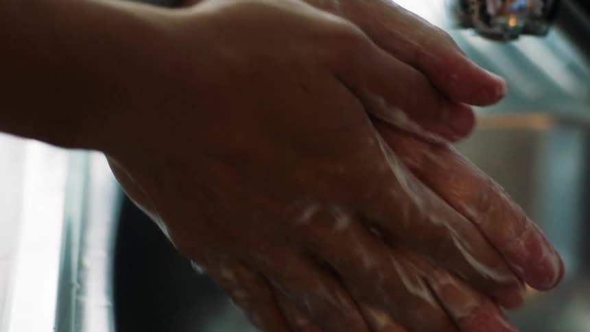 Man washes hands with soap in the kitchen