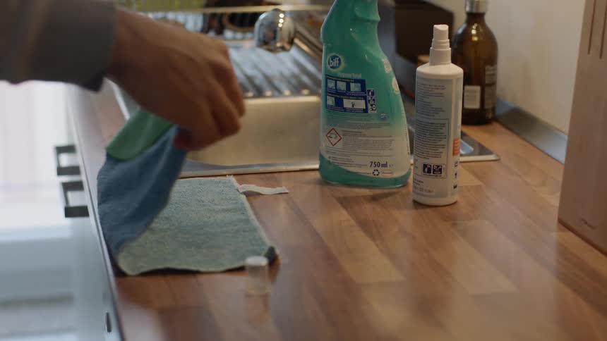 Man folds kitchen towel on counter top near sink after cleaning