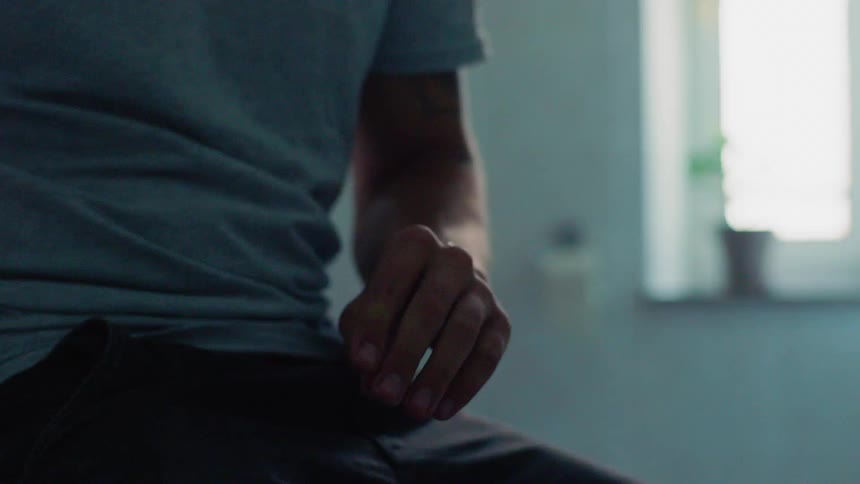 Man sitting in a room applies lotion on his hands