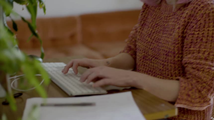 A woman works at a computer in a living room