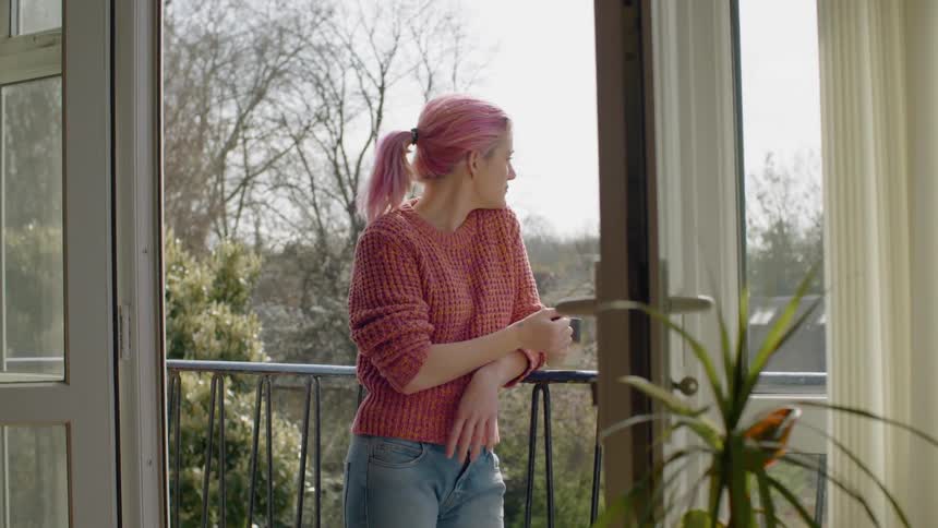 Pink haired female standing in her balcony