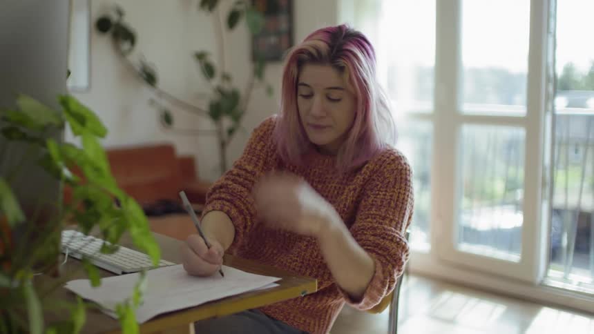 A girl is looking at a computer and taking notes