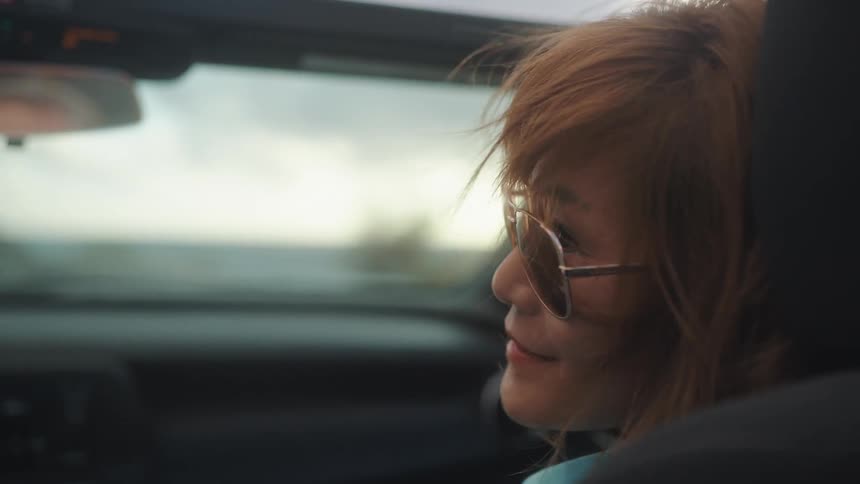 Woman wearing sunglasses rides passenger seat on sports car