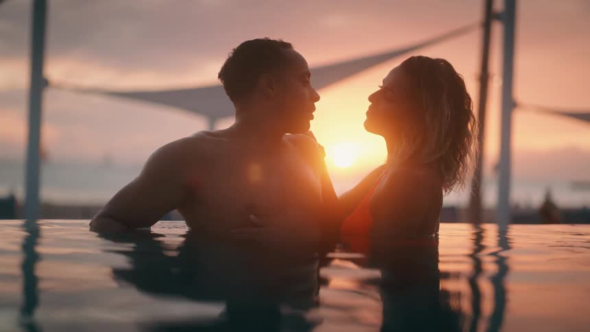 A man and woman are in the lake together during sunset