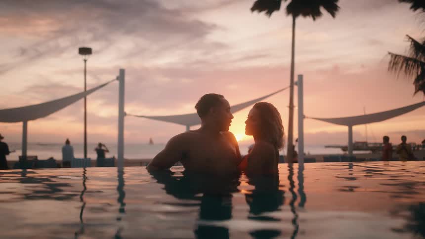 A man and woman are in the beach water together