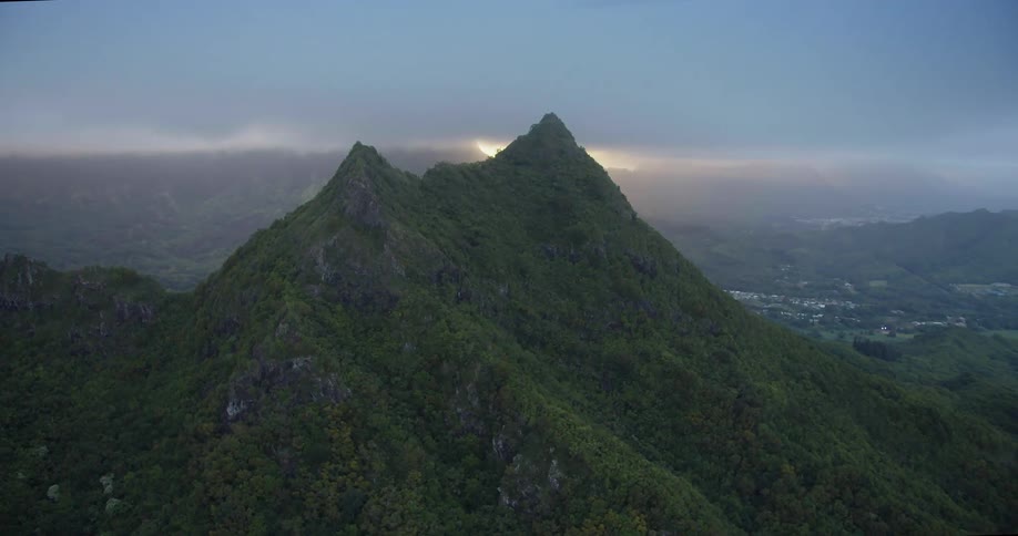 A mountain ridge covered in greenery just outside of a small town