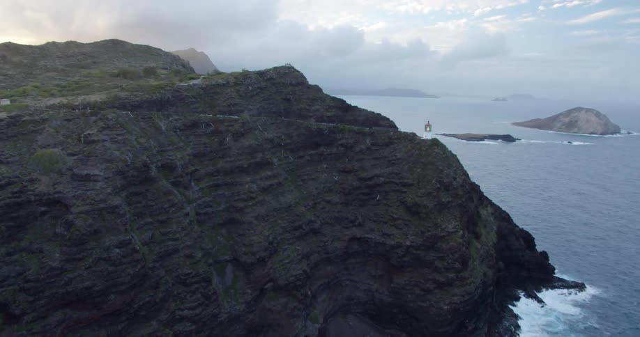 A lighthouse stands on a cliff facing the ocean