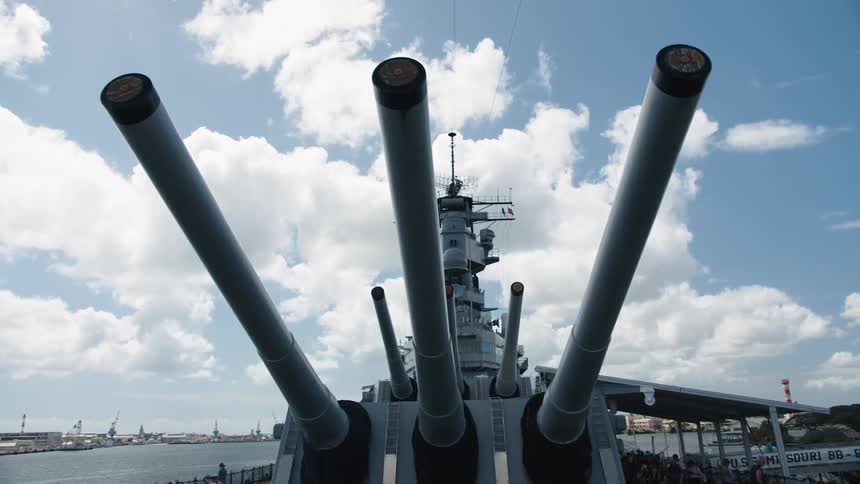 Rows of large guns on a docked battleship