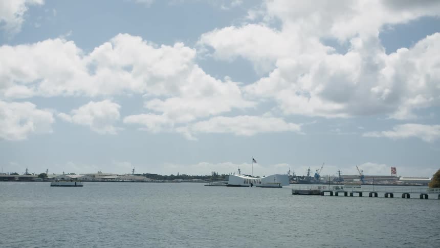 A coast with a pier with land and the sky in the background
