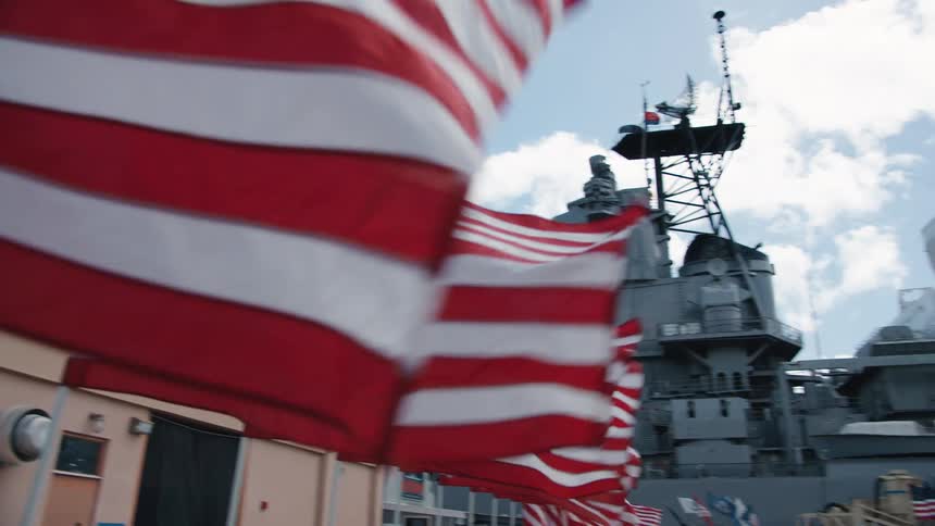 American flags fly next to a battleship
