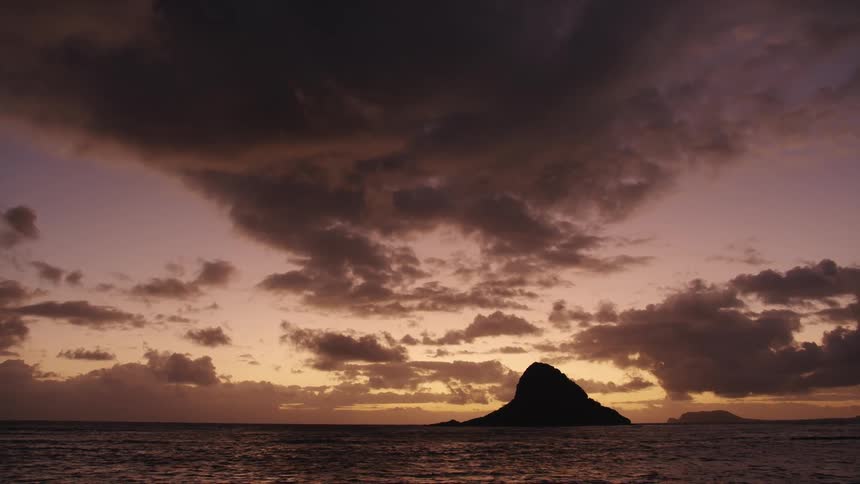 Small island silhouetted against sunset